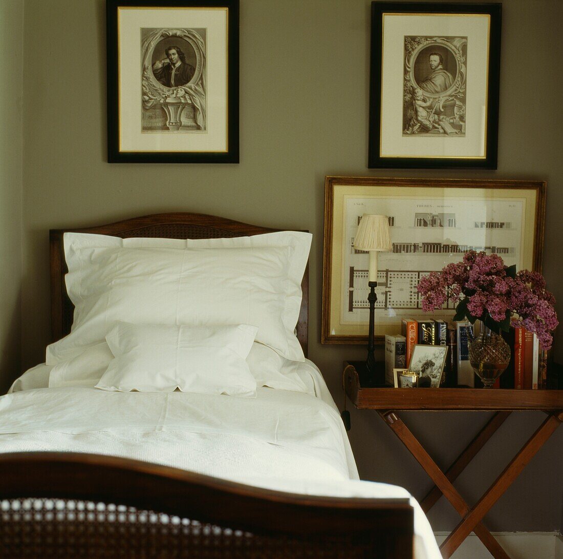 Einzelbett und klappbarer Nachttisch mit Kunstdrucken