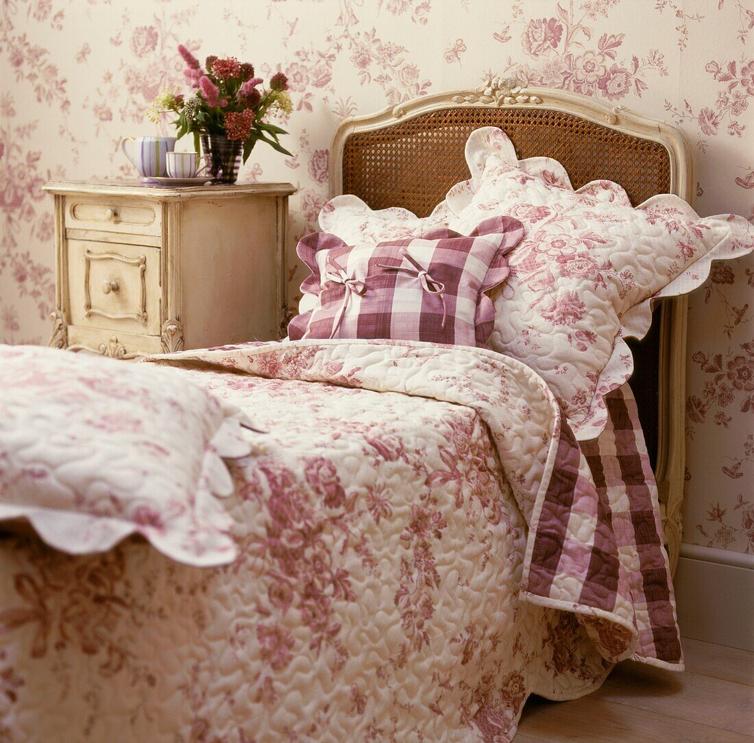 Geblümte Bettwäsche auf einem Einzelbett in Rosa und Weiß mit passender Tapete