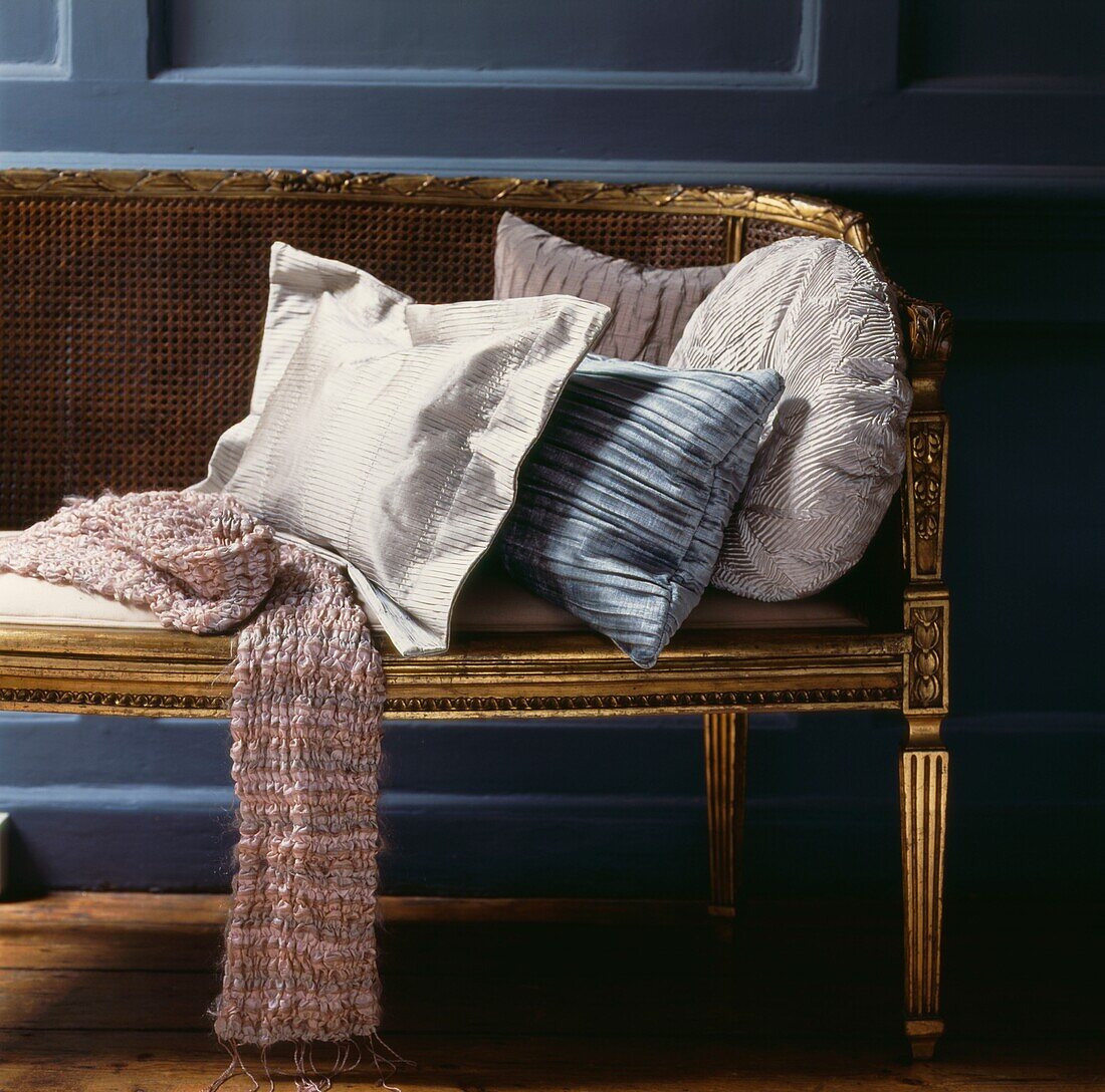 Wollschal auf vergoldetem Sofa mit Kissen in kontrastierenden Formen