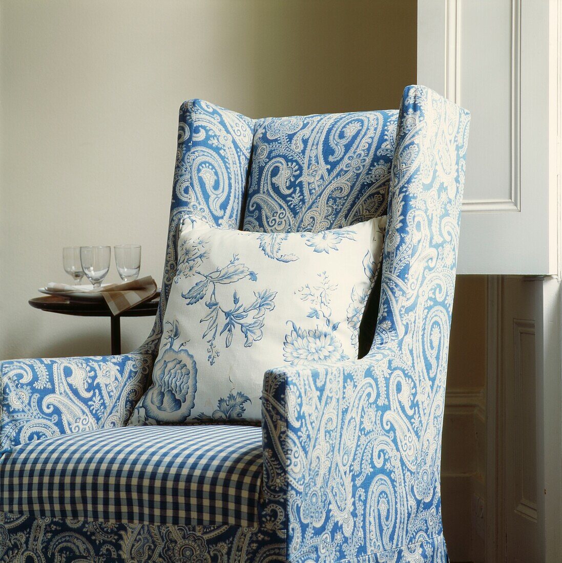 Blue paisley armchair with contrasting cushion and side table at window