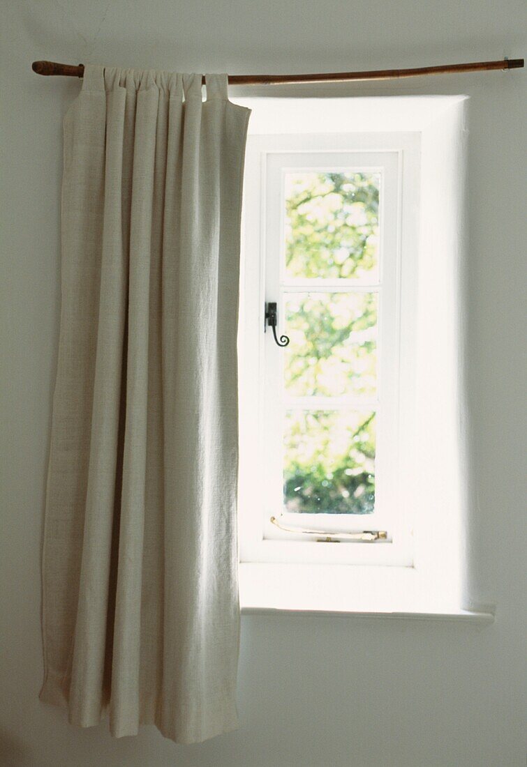 Neutral curtains at sunlit window with latch