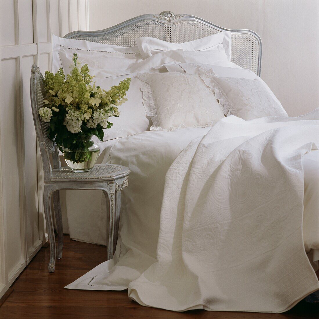 Flower arrangement on chair beside unmade bed