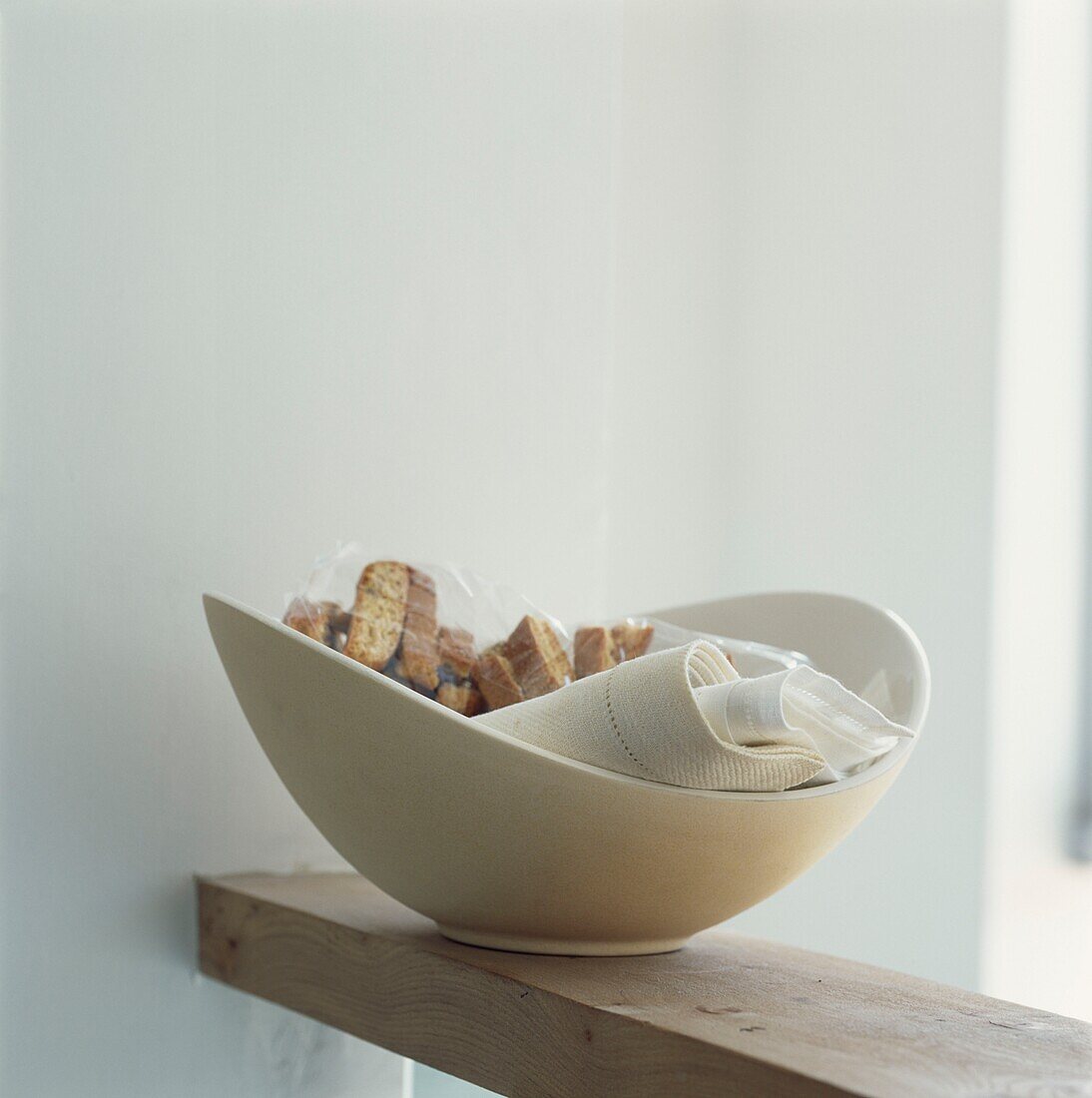 Confectionary and napkins in white bowl on wooden shelf
