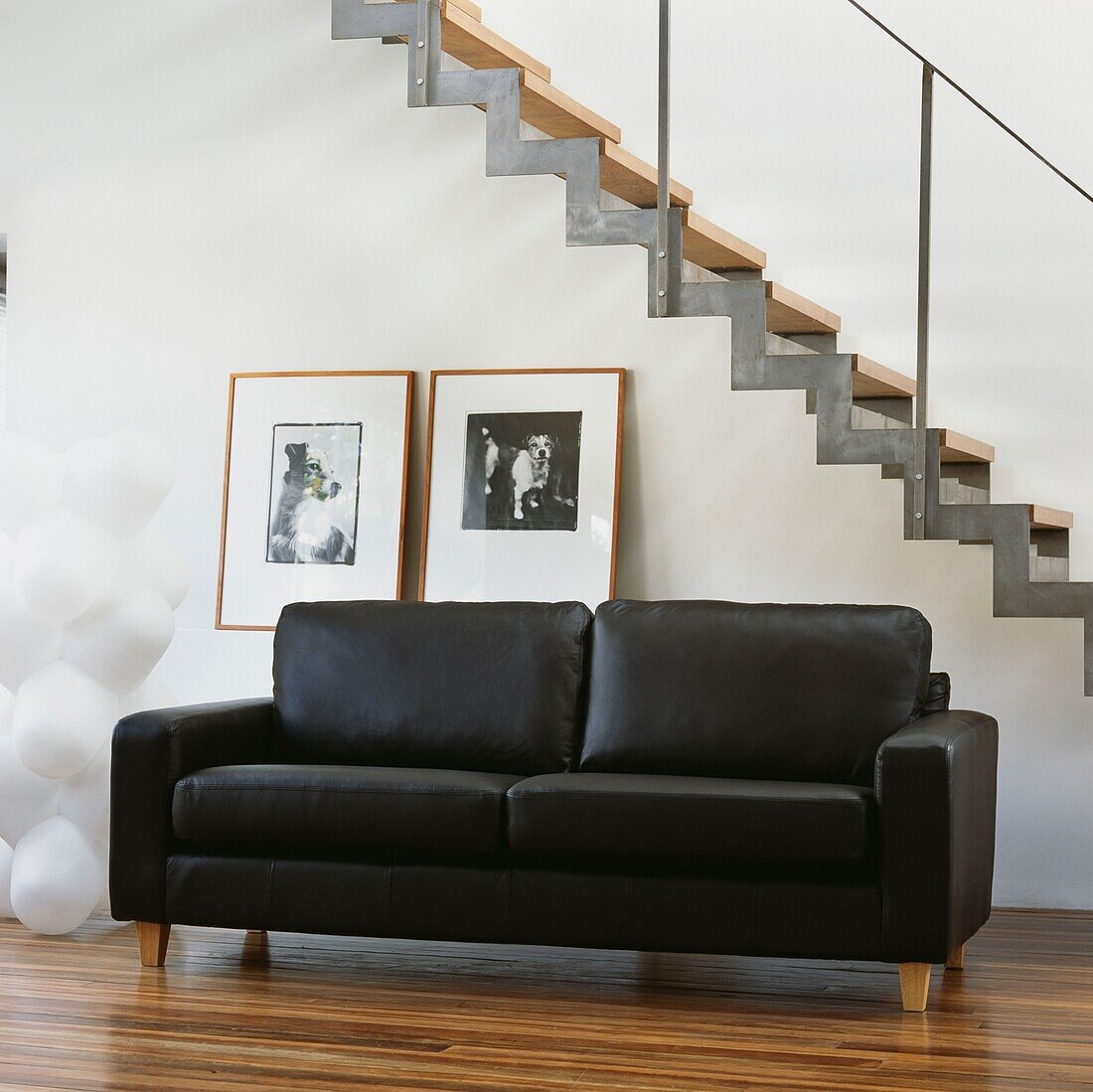 Black leather sofa by staircase and Tom Dixon light
