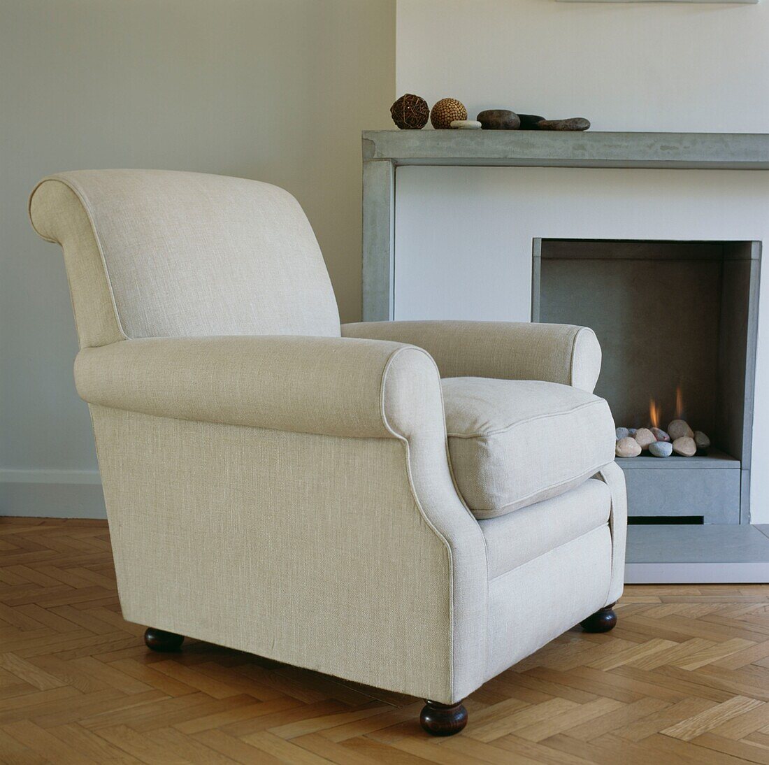 Cream upholstered armchair beside modern fireplace