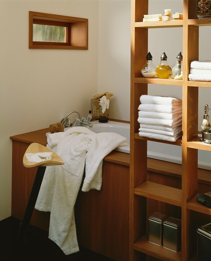 Morgenmantel und Hocker mit Ablage in einem Badezimmer aus hellem Holz