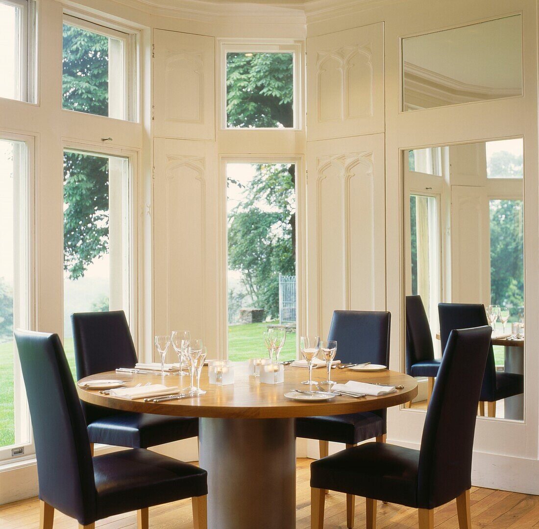 Black leather chairs at contemporary dining table with mirror set in shuttered bay windows