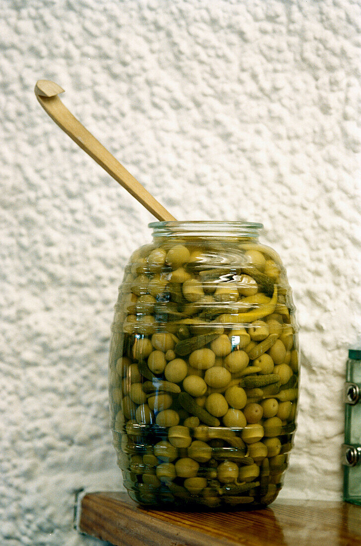 Glasgefäß mit grünen Oliven und Löffel