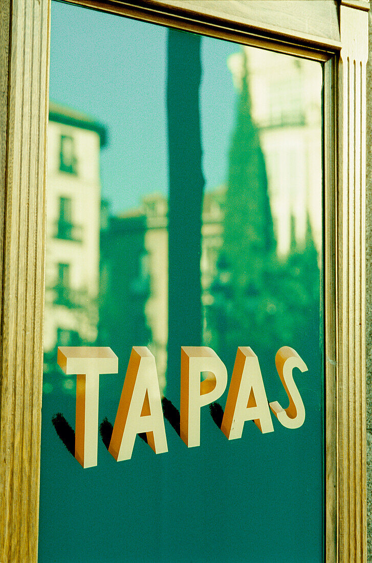 Buildings reflected onto the window of a tapas a bar in Madrid
