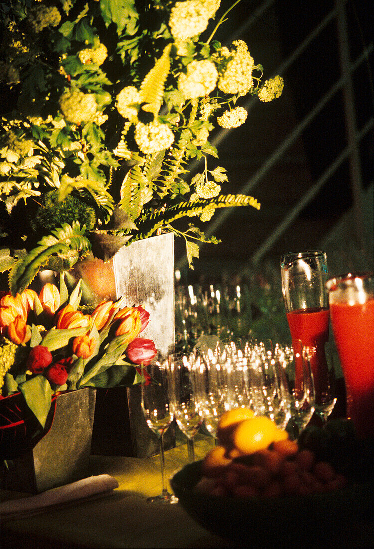 Blumen neben Obst und Weingläsern auf einer Party
