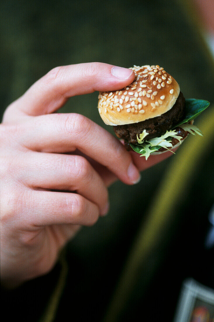 Party guest holding a mini hamburger