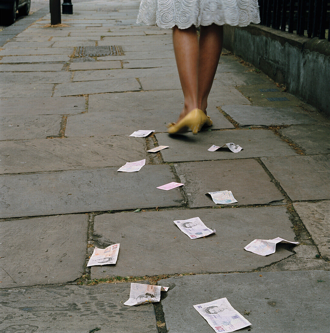 Frau beim Spazierengehen, die Geld und Kreditkarten auf der Straße fallen lässt