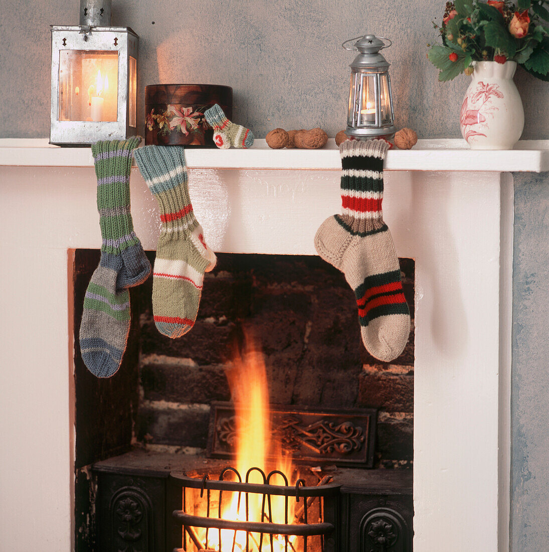 Weihnachten in einem Cottage mit handgestrickten gestreiften Socken auf dem Kaminsims über dem offenen Feuer