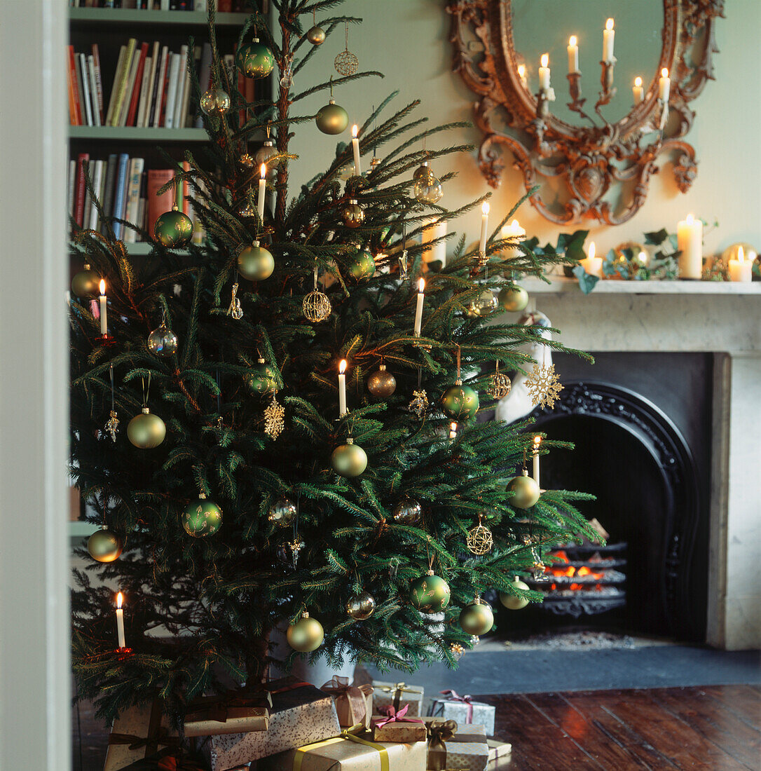 Weihnachtsbaum und Geschenke vor einem beleuchteten Kamin im Wohnzimmer