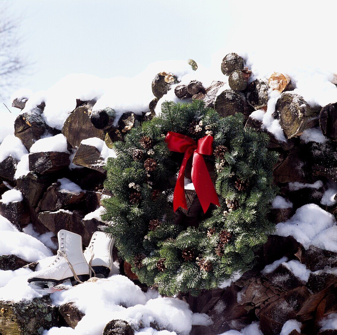 Log pile with Festive Evergreen wreath in snow