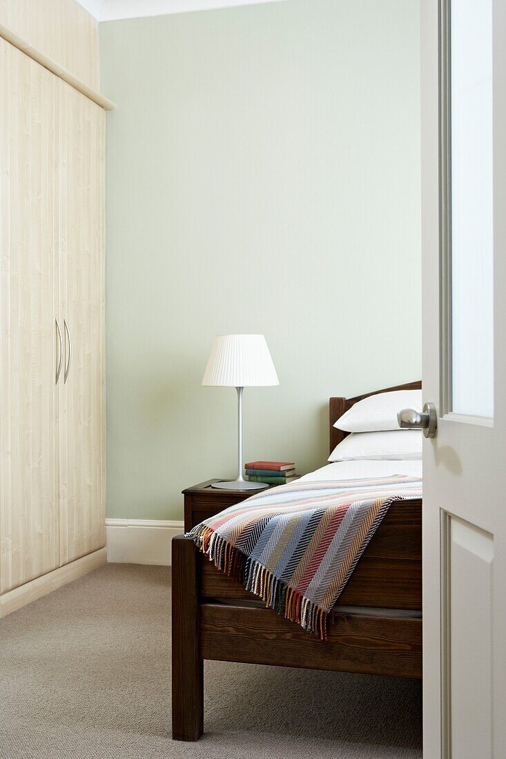 Decke auf Holzbett in pastellgrünem Schlafzimmer London England