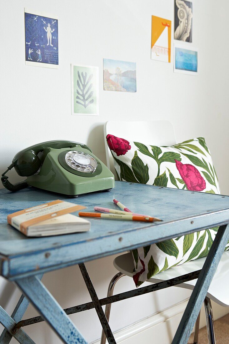 Floral cushion and table with rotary dial telephone with postcards in London home