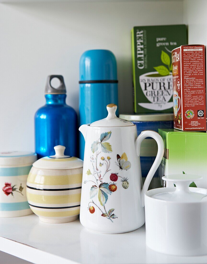 Coffeepot and flasks with boxes of teabags on kitchen shelf