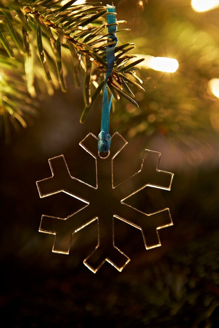 Transparent snowflake decoration hanging from Christmas tree in London home   UK