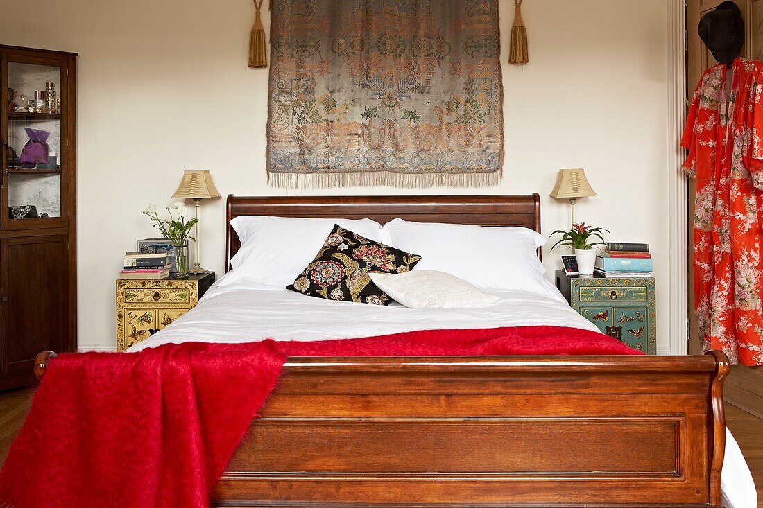 Orientalische Stoffe im Schlafzimmer mit antikem Holzbett und Eckschrank in einem Londoner Haus UK