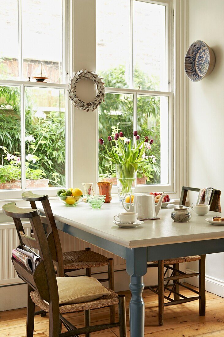 Kieferstühle am bemalten Küchentisch im Fenster eines Londoner Hauses UK