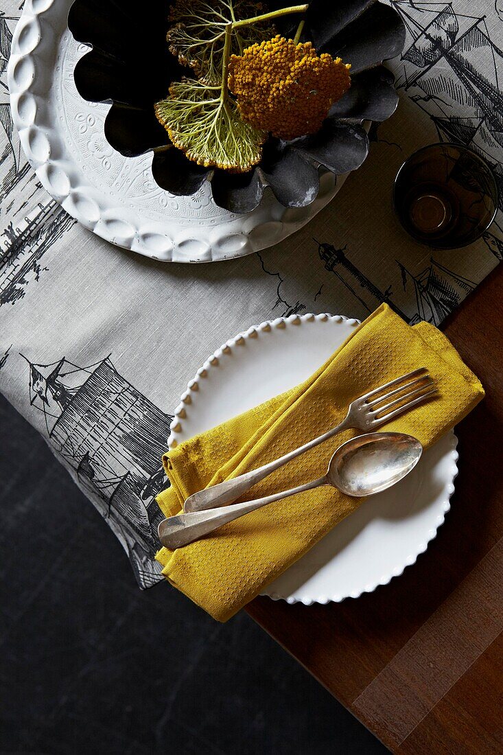Silberlöffel und -gabel im Vintage-Stil auf goldener Serviette mit Teller