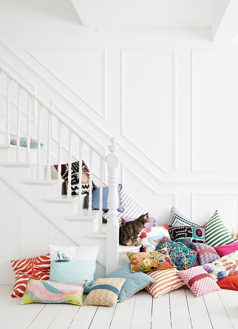 Verschiedene Kissen auf einer weiß gestrichenen Treppe in einem Einfamilienhaus