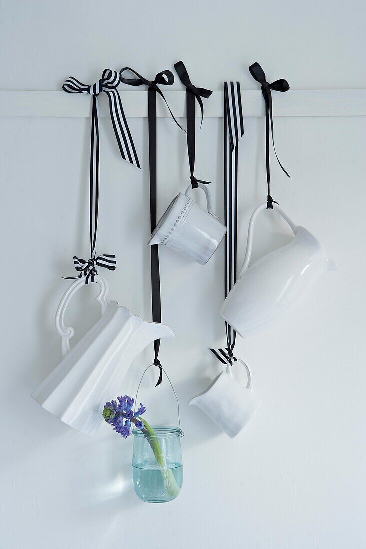 Weiße Milchkännchen und einstielige Blumen mit schwarzem und gestreiftem Schleifenband