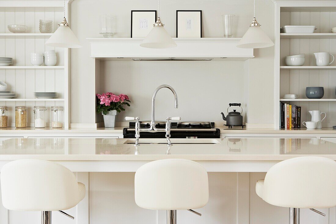 Bar stools in kitchen with white panelled shelving in contemporary home