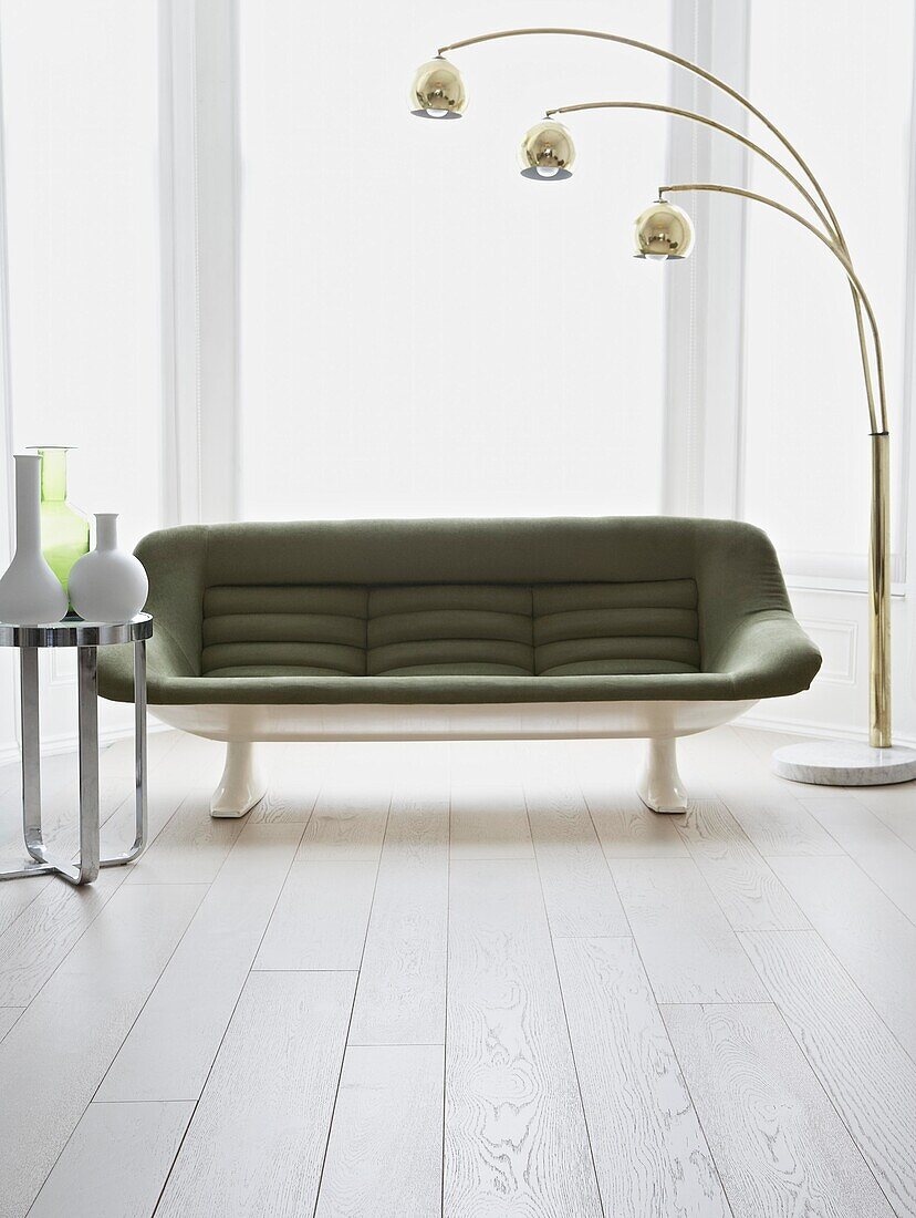 Grünes Sofa im Retrostil im Wohnzimmer mit weiß gestrichenen Dielenböden