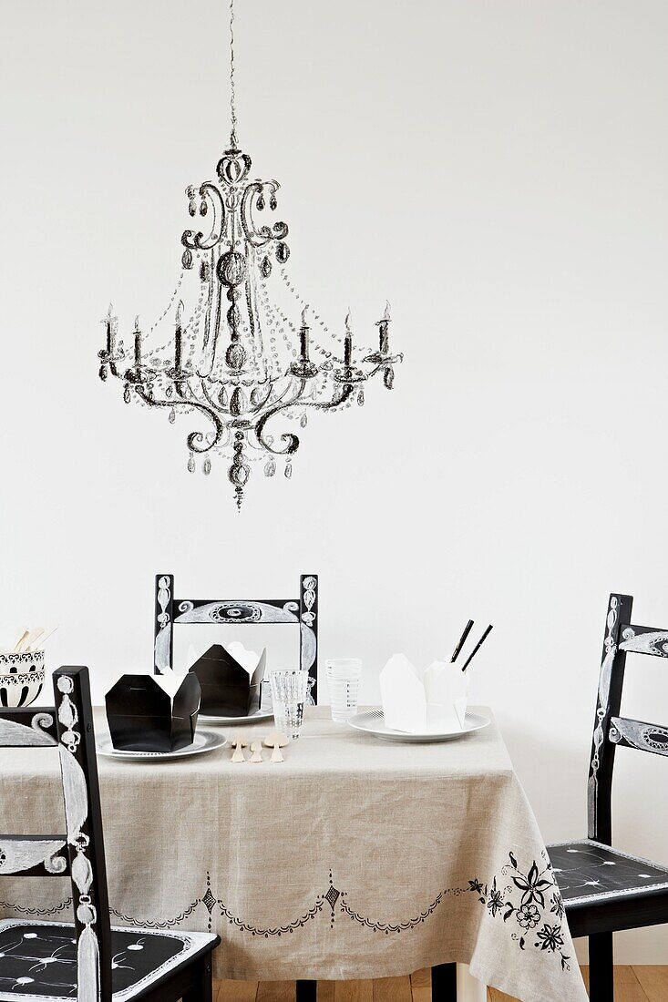 Personalisierte Stühle am Tisch mit Kronleuchter-Schablone auf weißer Wand
