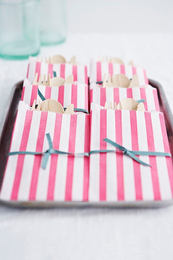 Disposable cutlery in pink striped paper bags