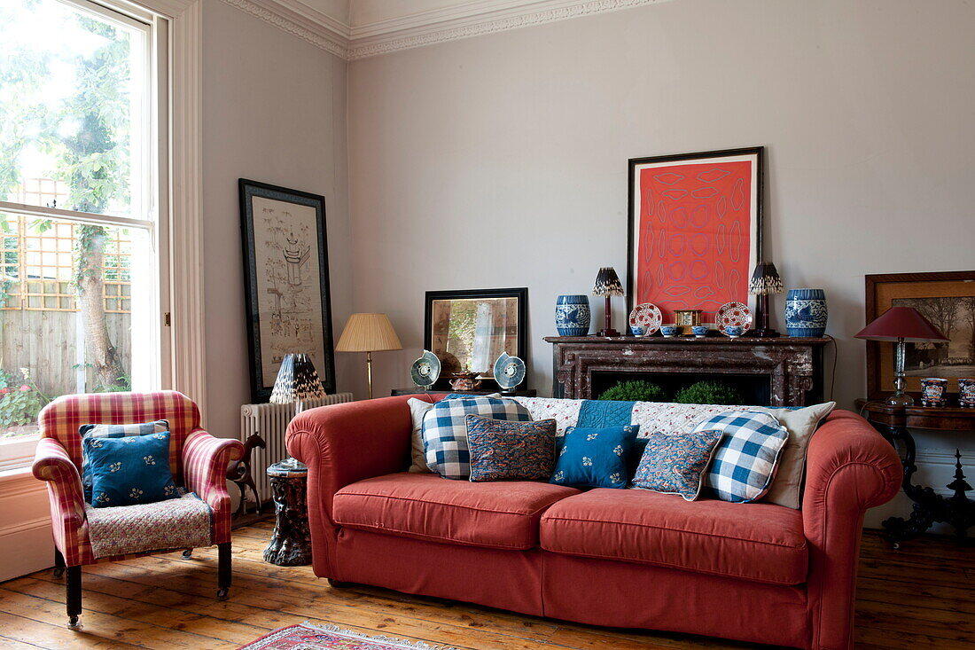 Red sofa and artwork at large sash window in Greenwich home,  London,  England,  UK