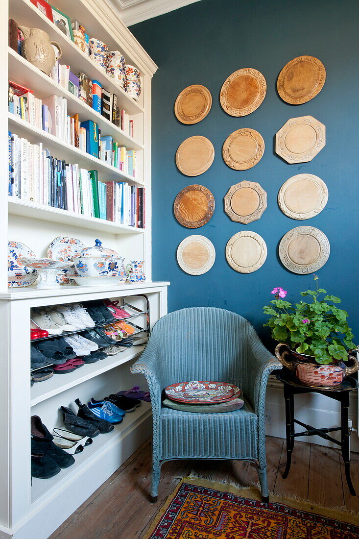 Blue chair in front of storage shelves with decorative wall mounted plaques in Greenwich home,  London,  England,  UK
