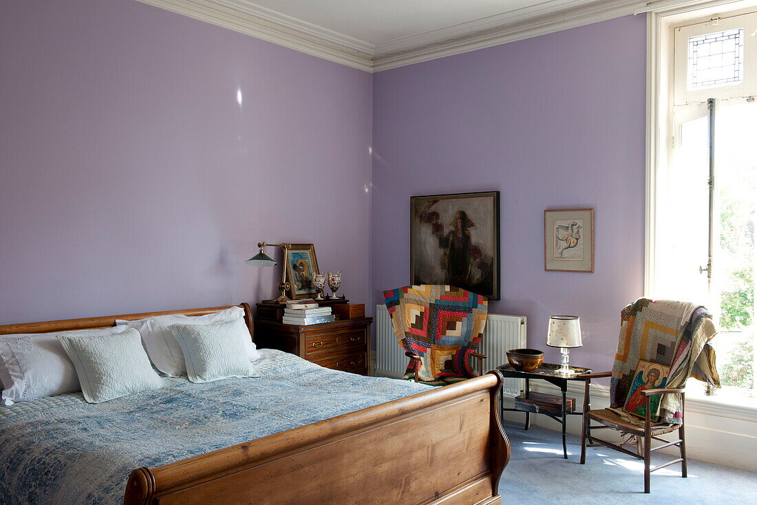 Hölzernes Doppelbett in fliederfarbenem Zimmer mit Patchwork-Decken über den Stühlen, Haus in Greenwich, London, England, UK