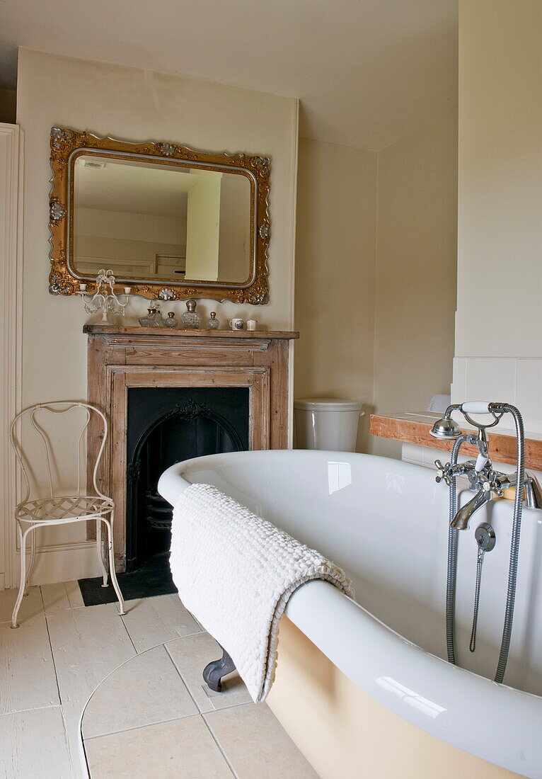 Spiegel mit vergoldetem Rahmen über dem Kamin im Badezimmer mit Badewanne in Ashford, Kent, England, UK