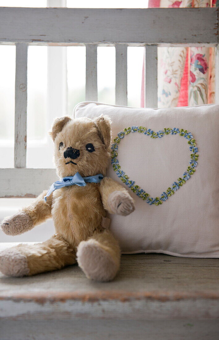 Teddybär mit Herzform auf Kissen im Kinderzimmer eines Hauses in Ashford, Kent, England, UK