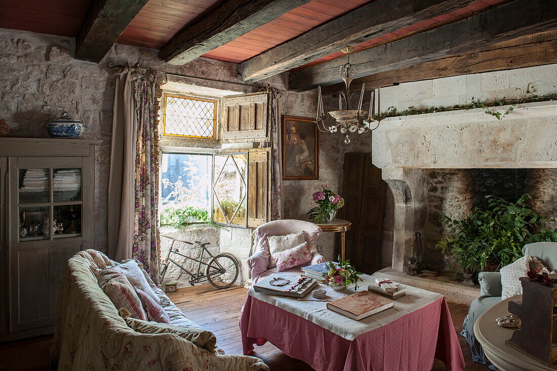 Wohnzimmer mit Balken und Fahrrad unter dem offenen Fenster in einem Bauernhaus aus Stein, Dordogne, Frankreich
