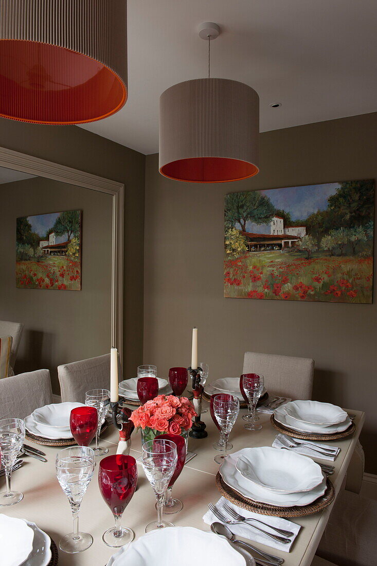Dining table with red wineglasses reflected in large mirror of Battersea home,  London,  England,  UK