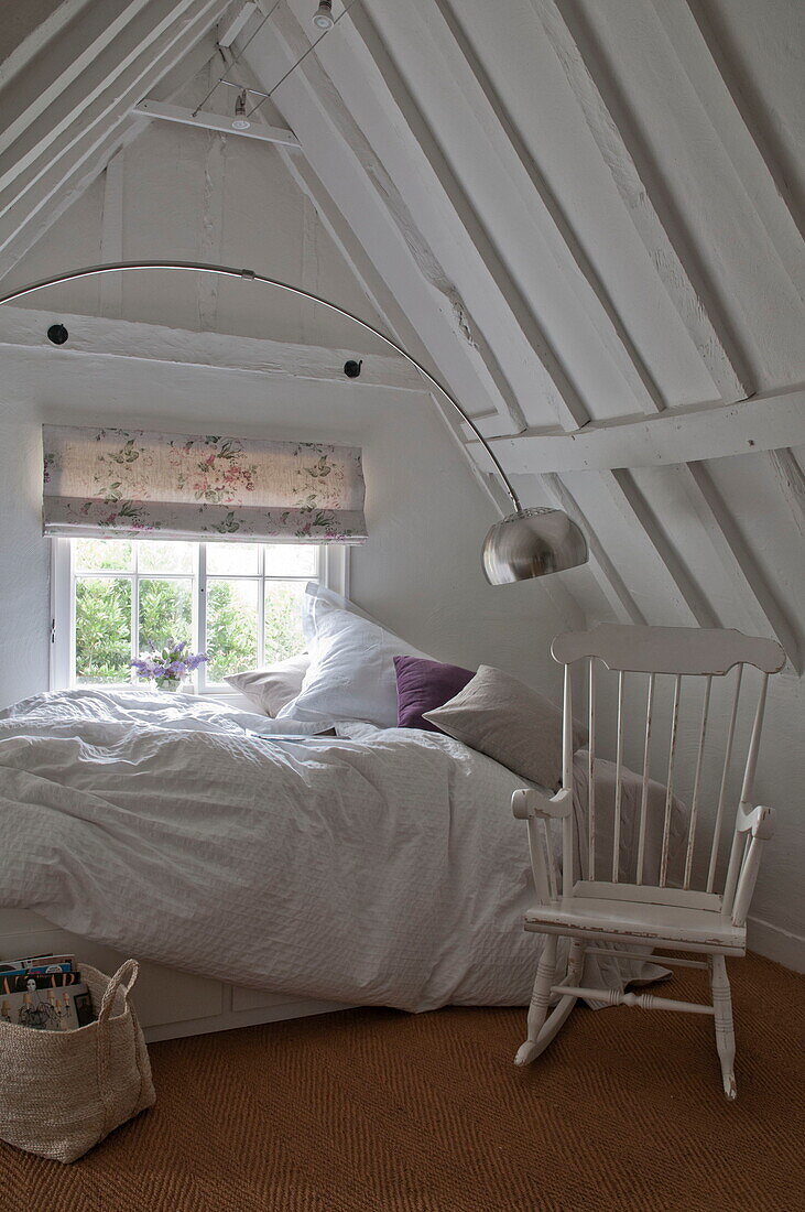 White painted rocking chair and unmade bed in attic bedroom of Kingston home,  East Sussex,  England,  UK