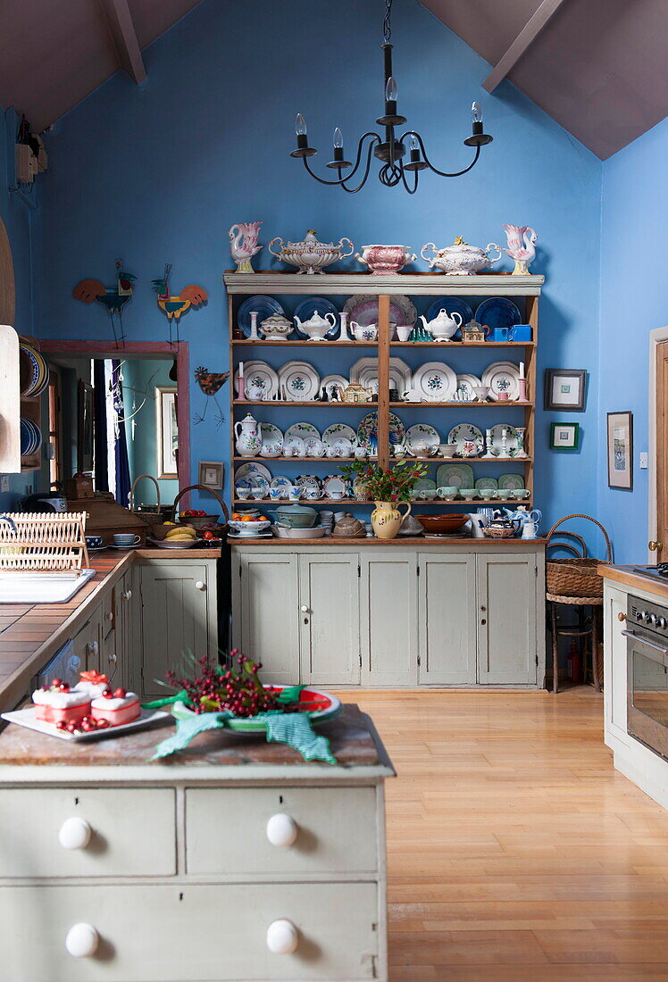 Geschirr auf einer Küchenkommode in einer blauen Küche mit doppelter Höhe in einem Bauernhaus in Tiverton, Devon, UK