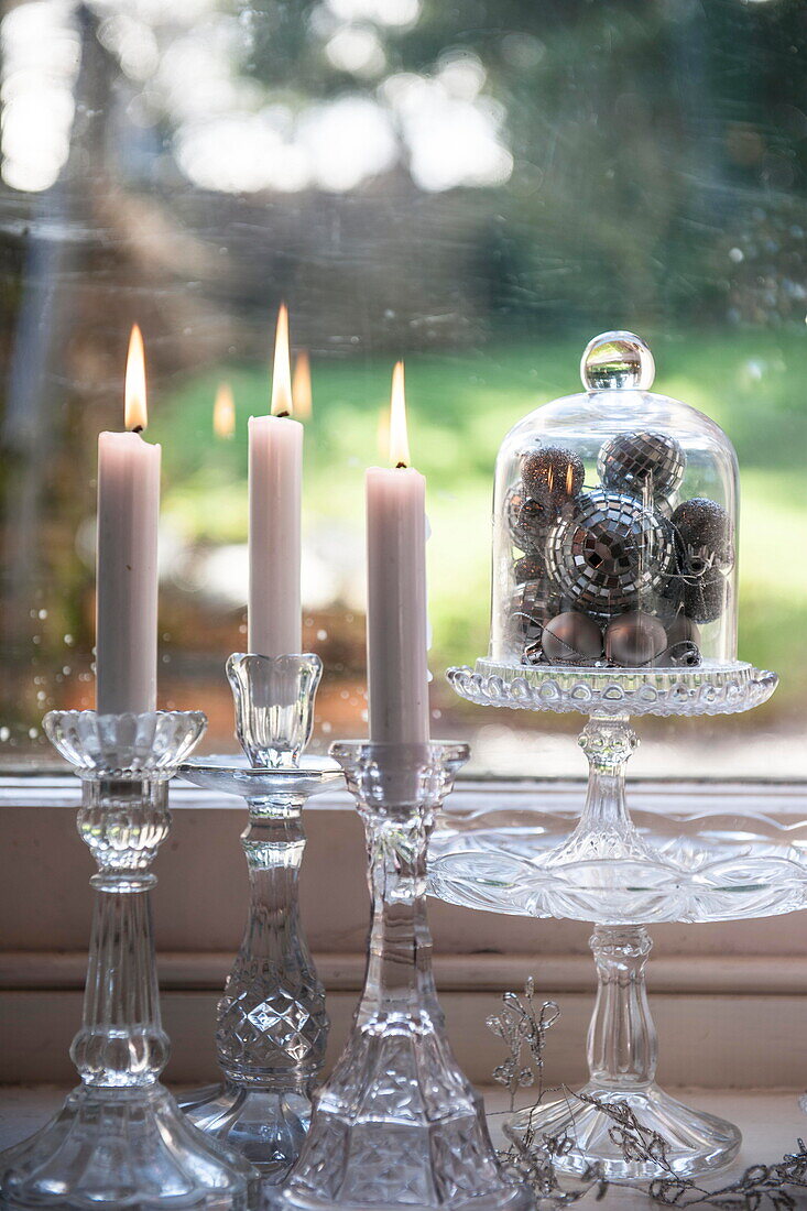 Beleuchtete Kerzen und Silberkugeln im Fenster des Bauernhauses in Tiverton, Devon UK