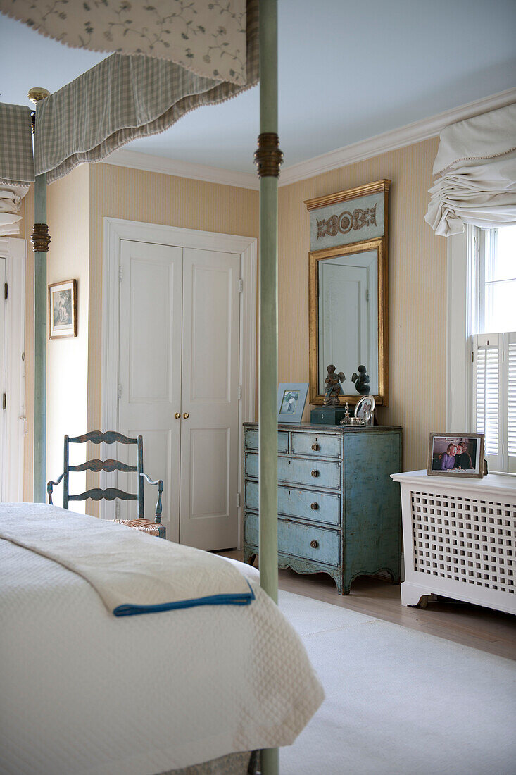 Salvaged chest of drawers with gilt framed mirror and four postered bed in Washington DC bedroom,  USA
