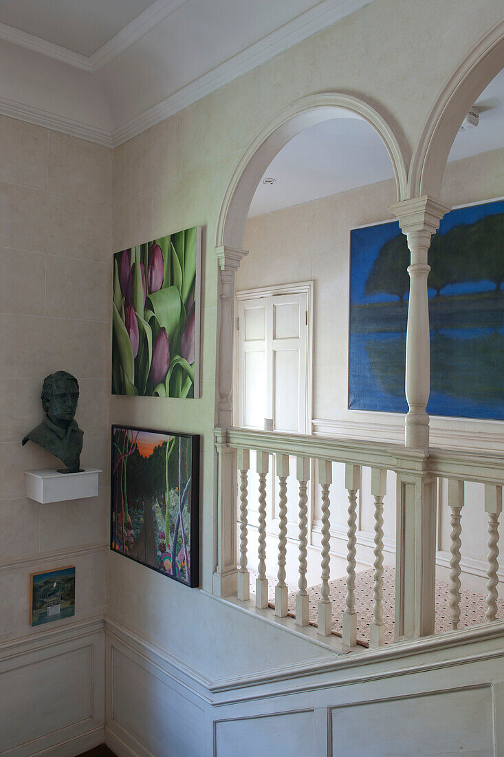 Modern art and arched banisters of white staircase detail in Tiverton country home,  Devon,  England,  UK
