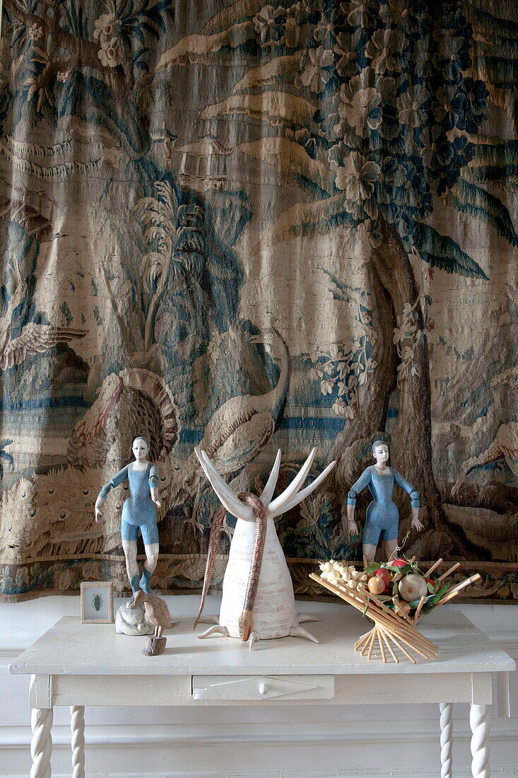 Figurines on side table with wall tapestry in entrance of Bordeaux apartment building,  Aquitaine,  France