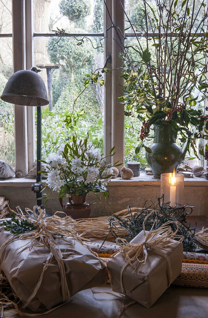 Christmas presents wrapped in brown paper on table at window of Benenden cottage,  Kent,  England,  UK