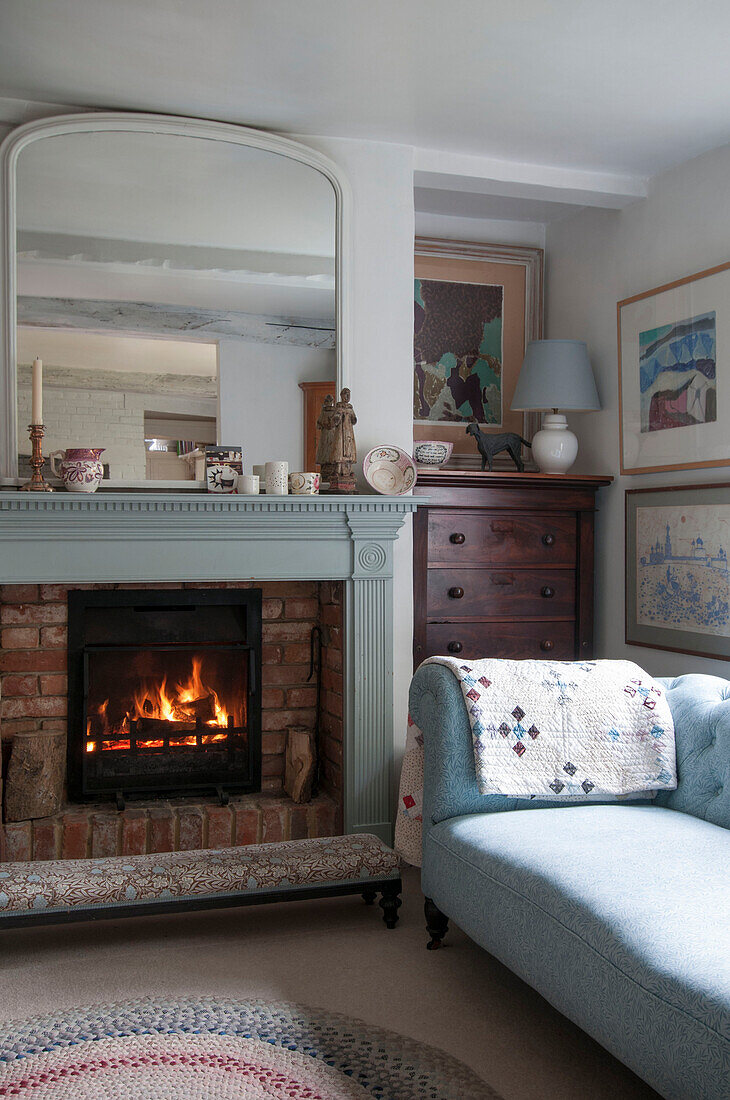 Großer Spiegel über beleuchtetem Kamin mit hellblauem Sofa in Dorset Wohnzimmer Kent UK