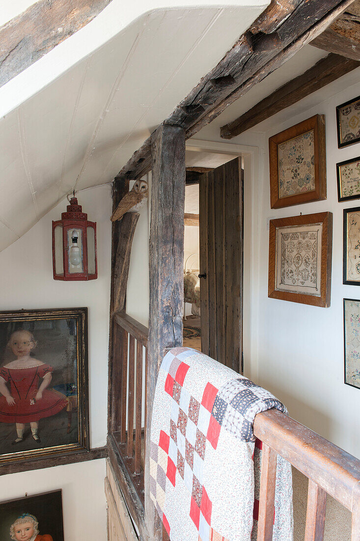 Gerahmte Stickerei mit Patchwork-Quilt über dem Treppengeländer in einem Bauernhaus in Ashford, Kent, Großbritannien