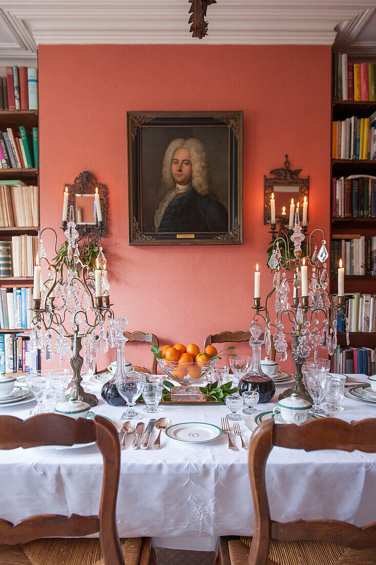 Esstisch mit Bücherregal und Glaskandelabern in einem Londoner Haus in England UK