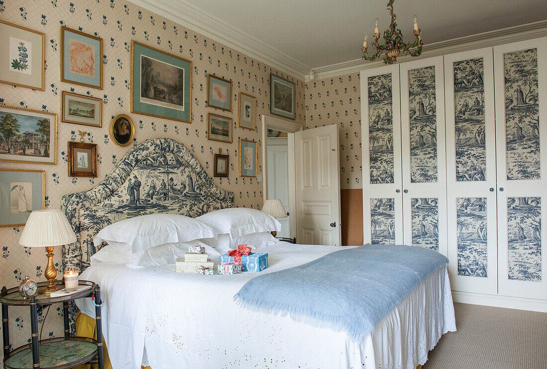 Toile de jouy headboard with matching papered wardrobe and framed artwork in London bedroom  England  UK